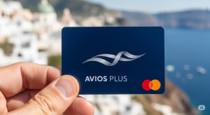 A person's hand holds a blue, Avios-inspired credit card in front of a blurred, sunny European coastal destination, representing the use of reward points for travel.